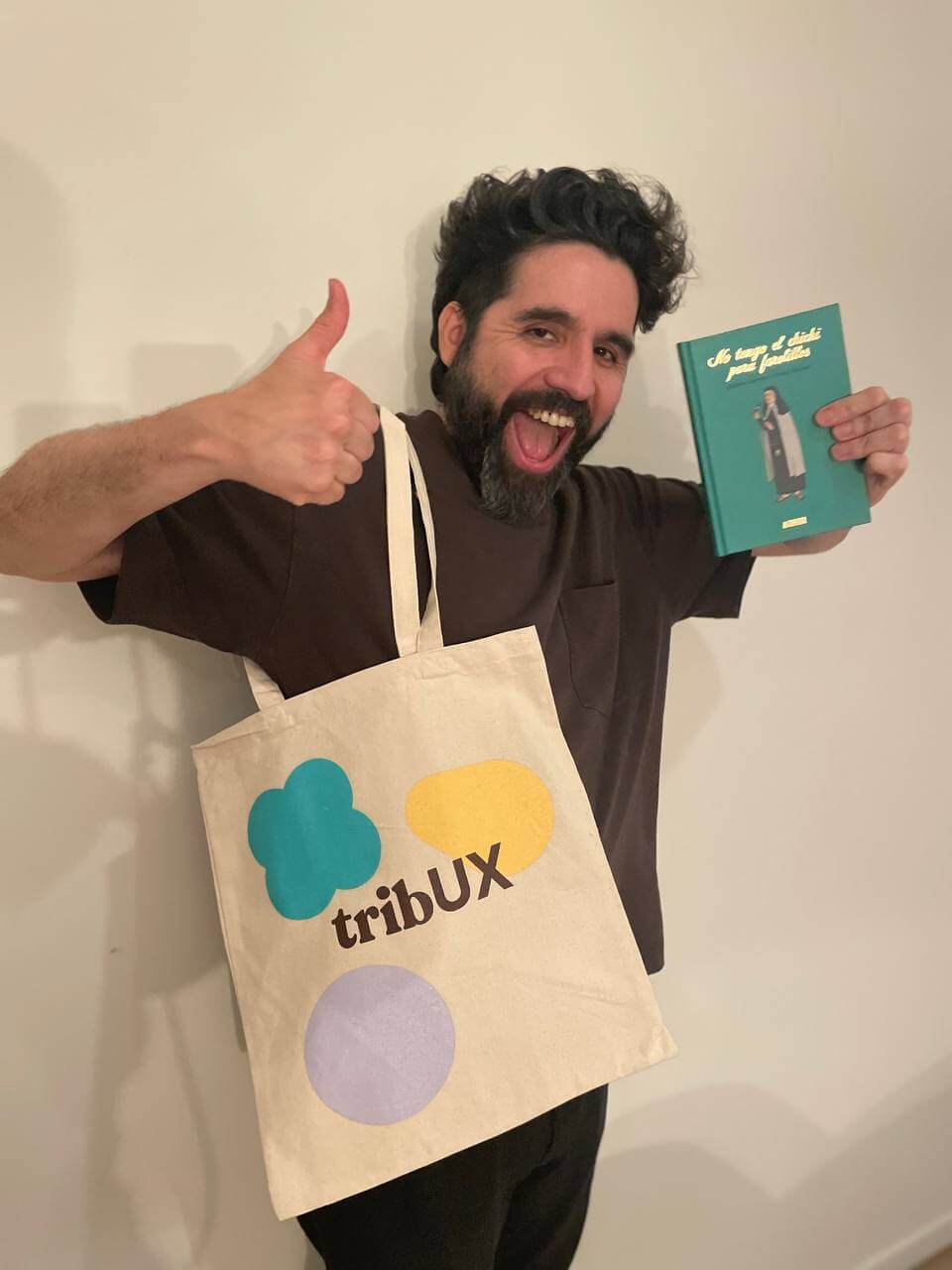 Hombre moreno con una bolsa y un libro en la mano